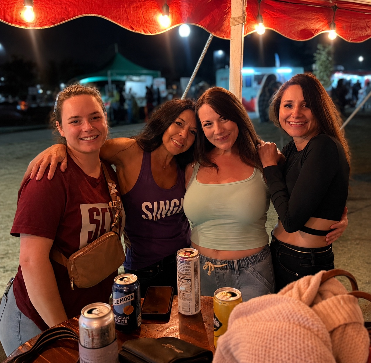 Four women smiling together at an outdoor Single & here to Mingle event